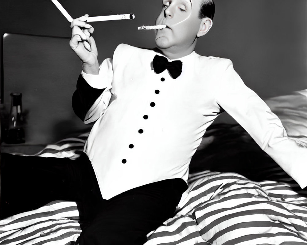 Monochrome image: man in tuxedo with long cigarette holder on striped bed