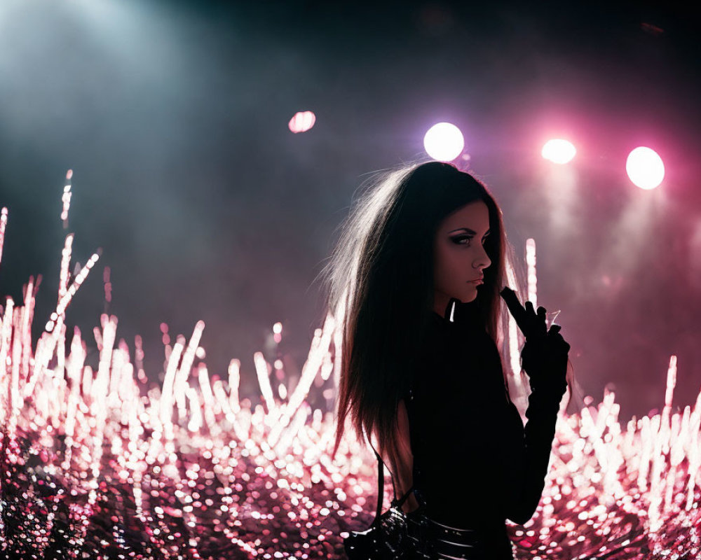 Pensive person with dark makeup under pink stage lights