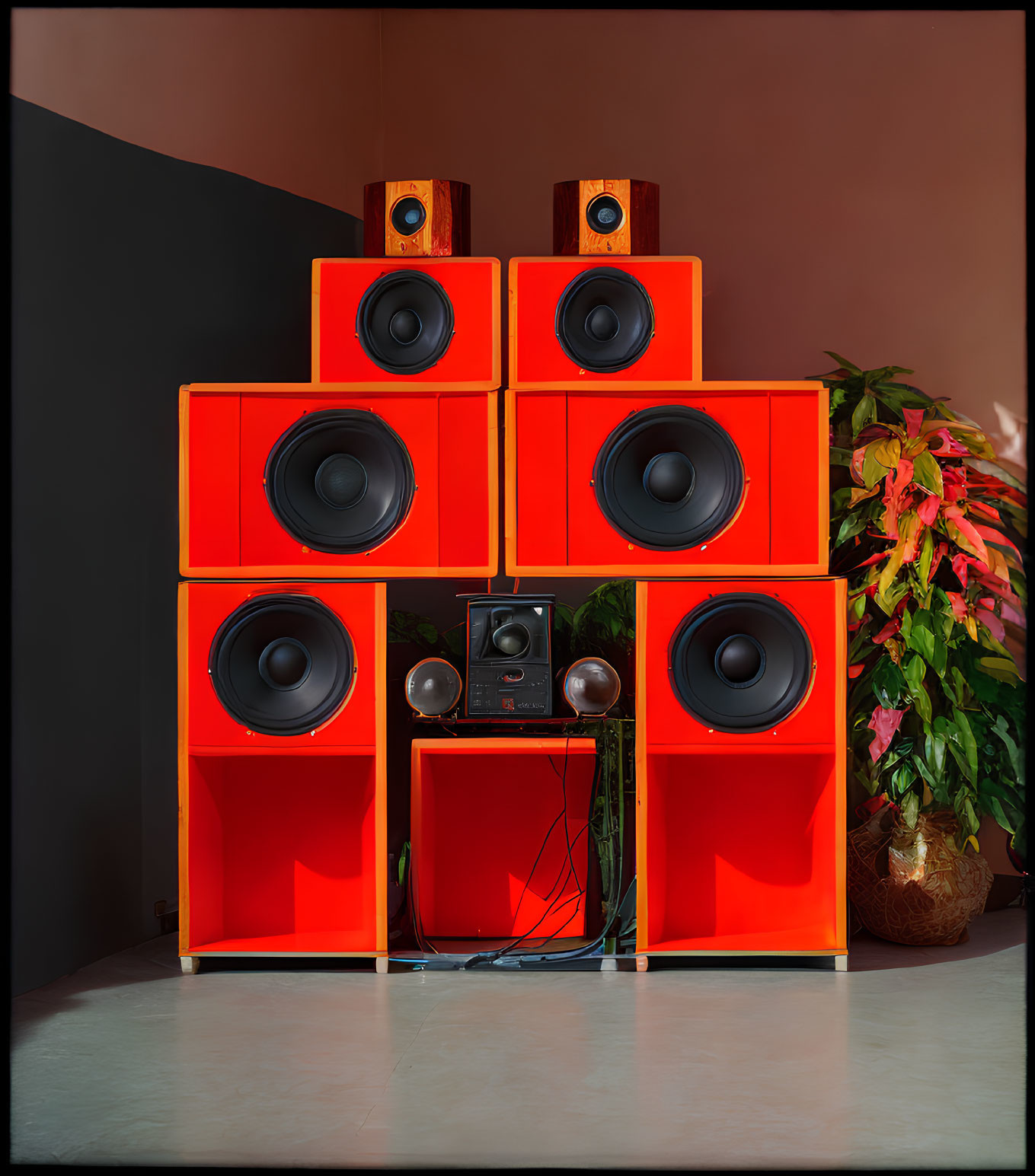 Red speakers on shelf with audio equipment against shadowed backdrop