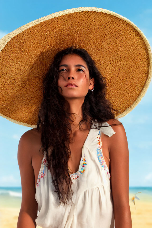 Young woman in straw hat and sundress on beach under clear blue sky