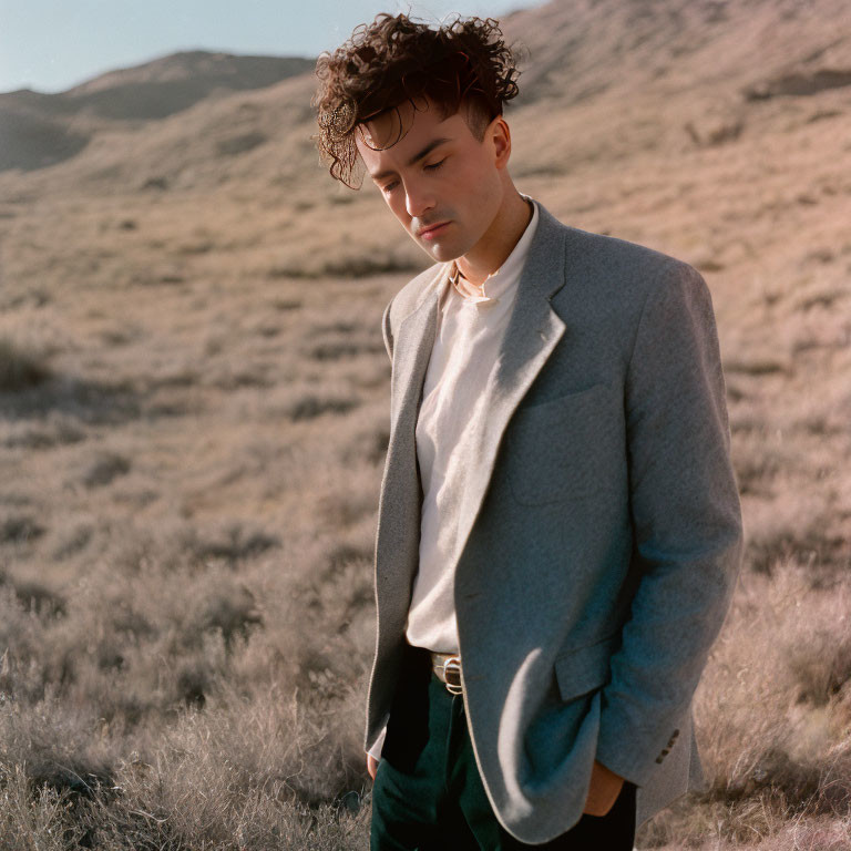 Curly-Haired Young Man in Gray Blazer Standing in Field