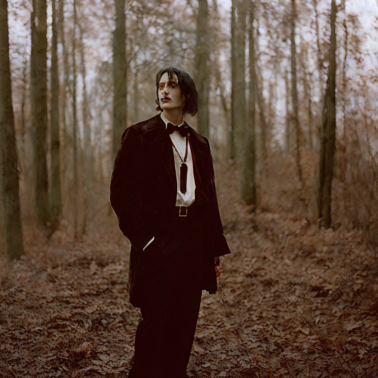 Person in dark suit standing in bare woodland, gazing thoughtfully.