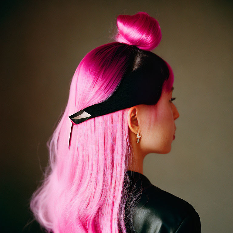 Profile of person with vibrant pink hair in top bun, black headband & clip