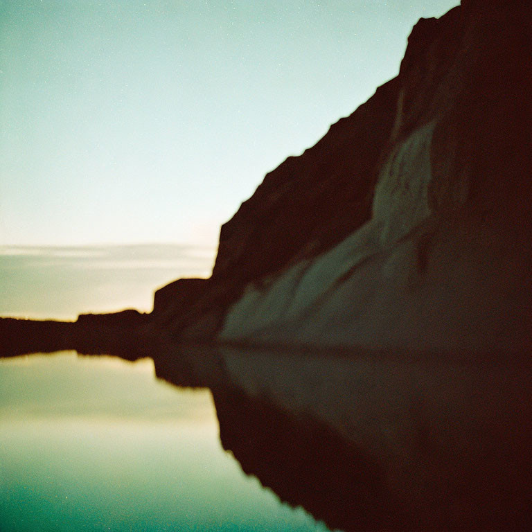 Blurred rock formation reflecting in still water at dusk