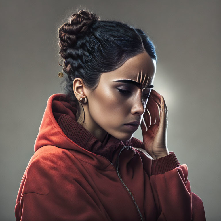 Contemplative woman with braided updo and sunglasses in red hoodie