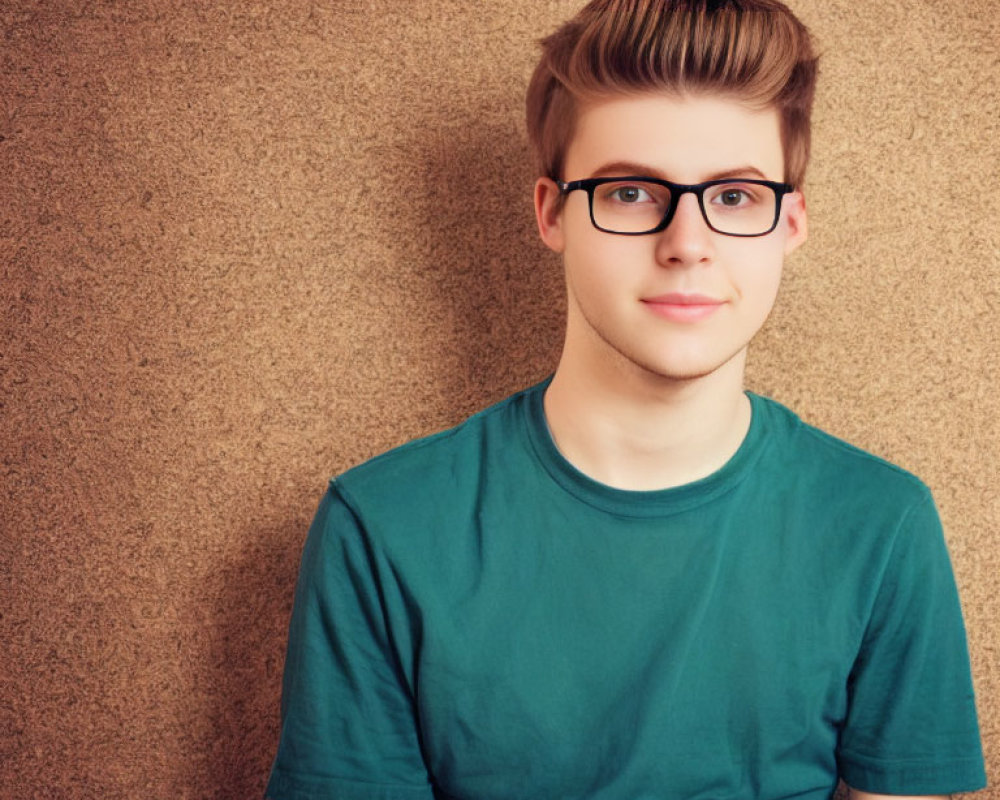 Stylish young man in green t-shirt and glasses on beige background