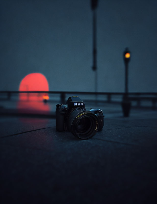 DSLR camera on ground with red circular light and street lamps in background