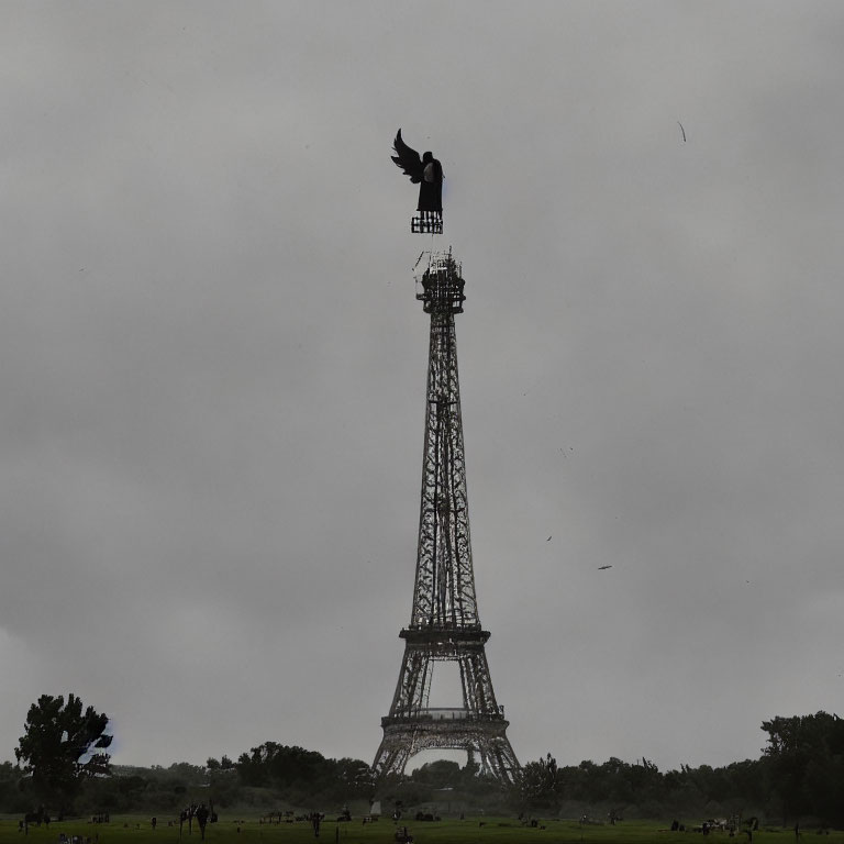 Bird on Eiffel Tower model in cloudy field