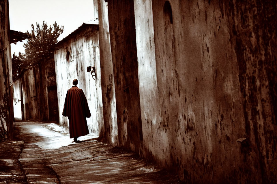 Mysterious figure in cloak strolls down narrow alley at night