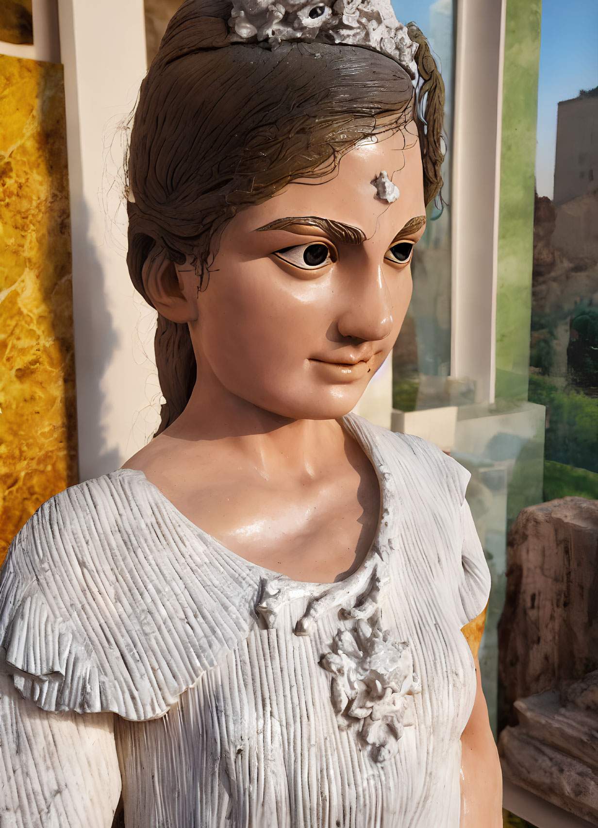 Detailed close-up of a statue with textured dress and headpiece in warm lighting