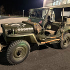 Vintage Military Jeep with Camouflage Paint and US Flag on Display