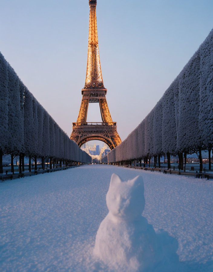 Snowcat sculpture on snowy path with illuminated Eiffel Tower at twilight