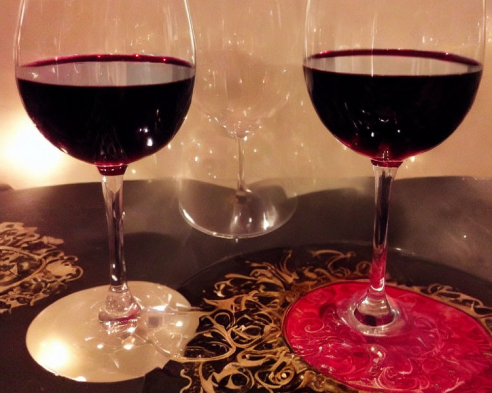 Elegant red wine glasses on table with ornate coasters