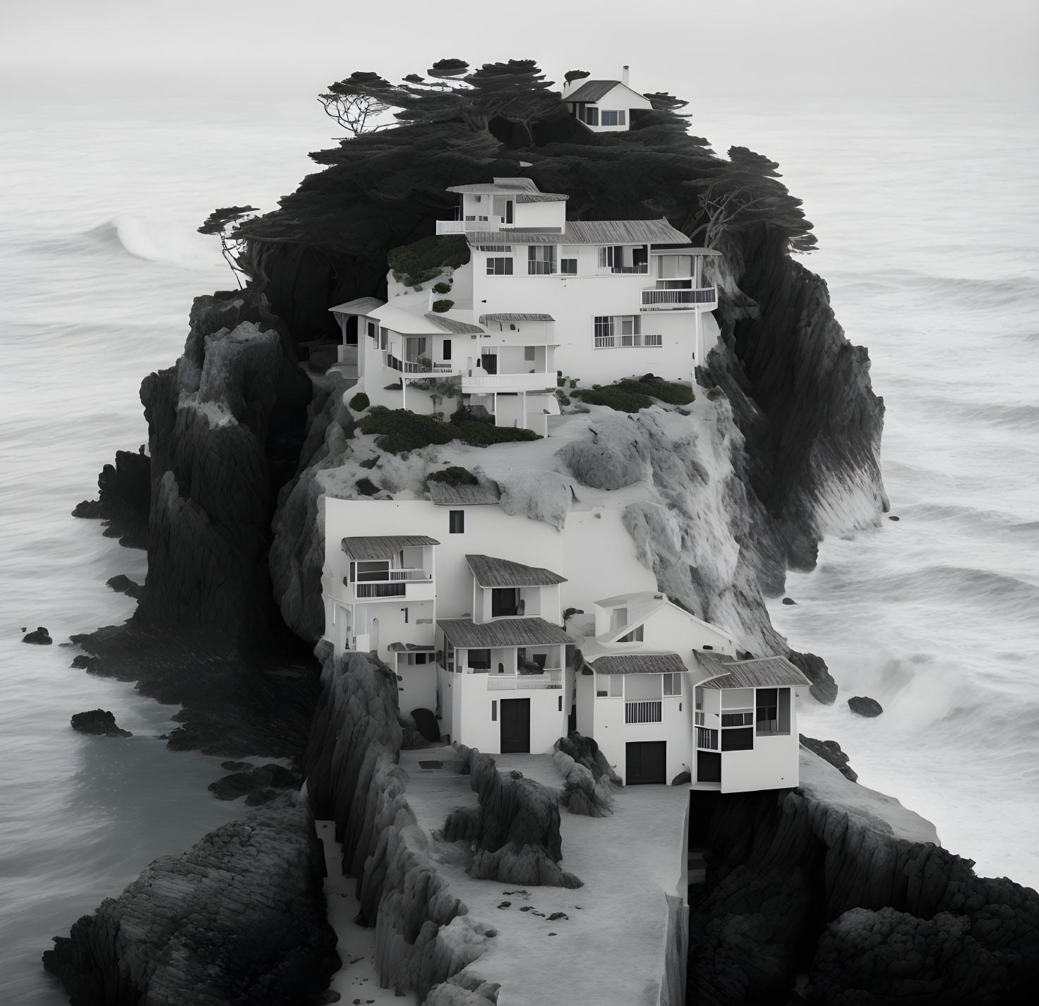 White modernistic buildings on rugged cliff overlooking misty ocean.