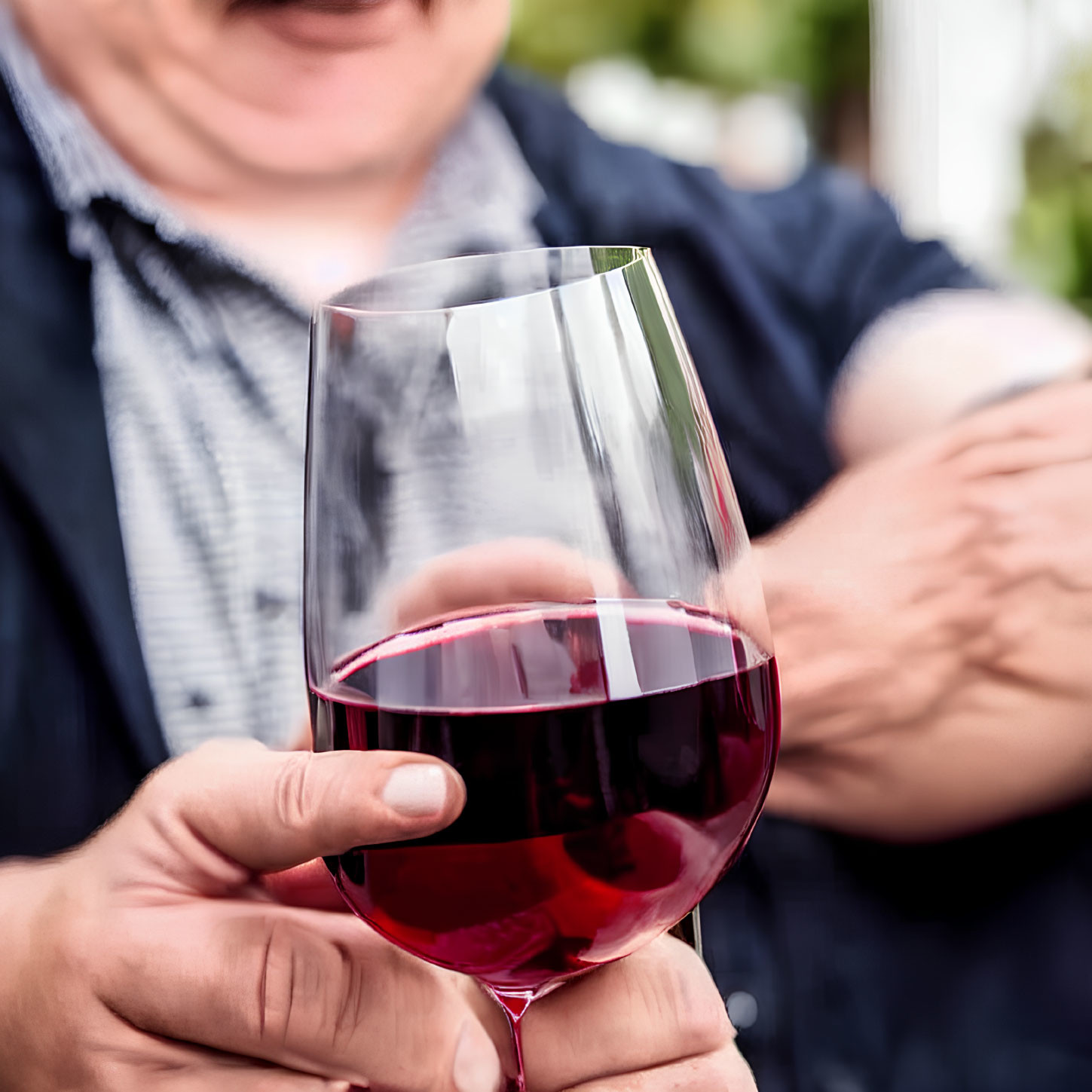 Person holding red wine glass in casual setting