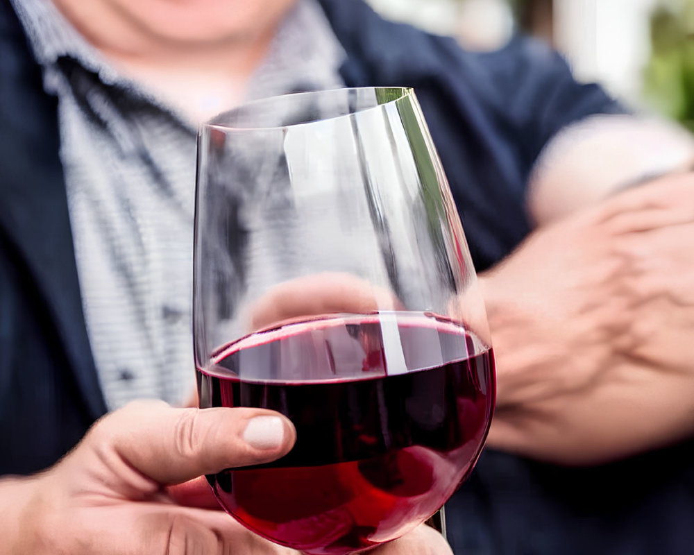 Person holding red wine glass in casual setting