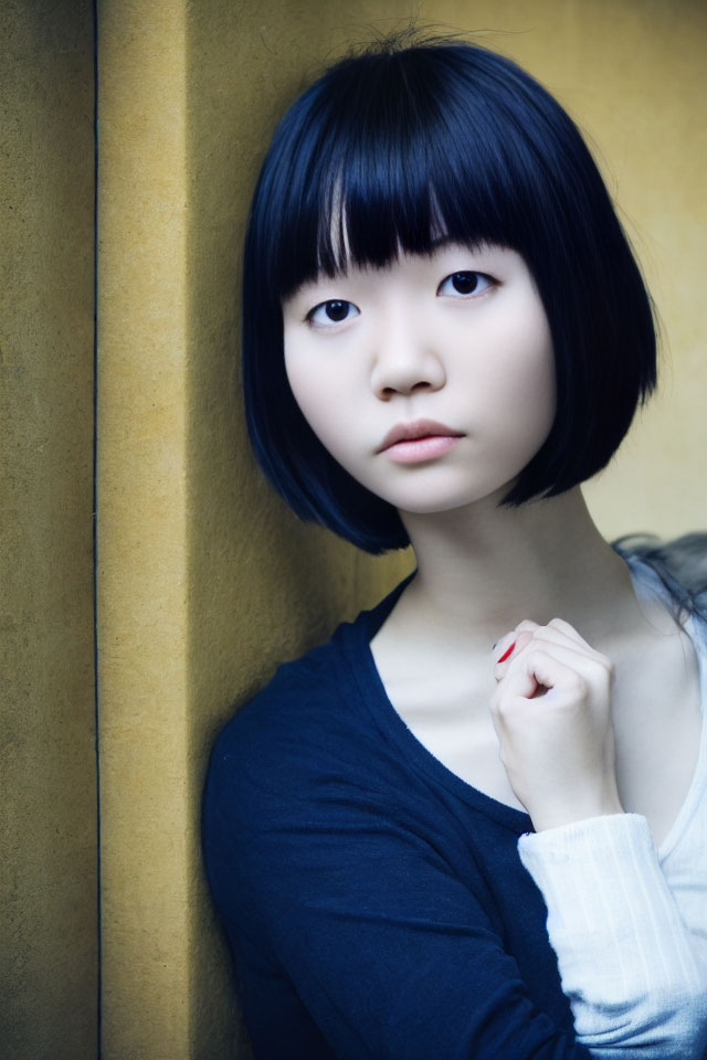 Pensive young woman with bob haircut against yellow wall
