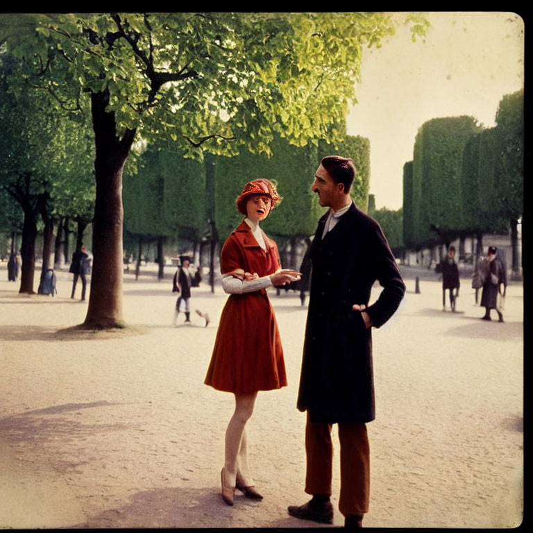Man in Coat and Woman in Red Dress Talking on Tree-Lined Path