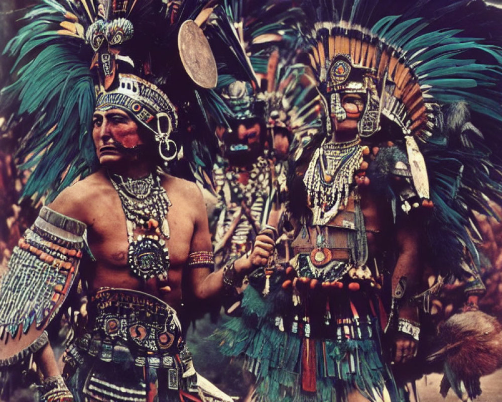 People in traditional indigenous attire with feathered headdresses and drum.