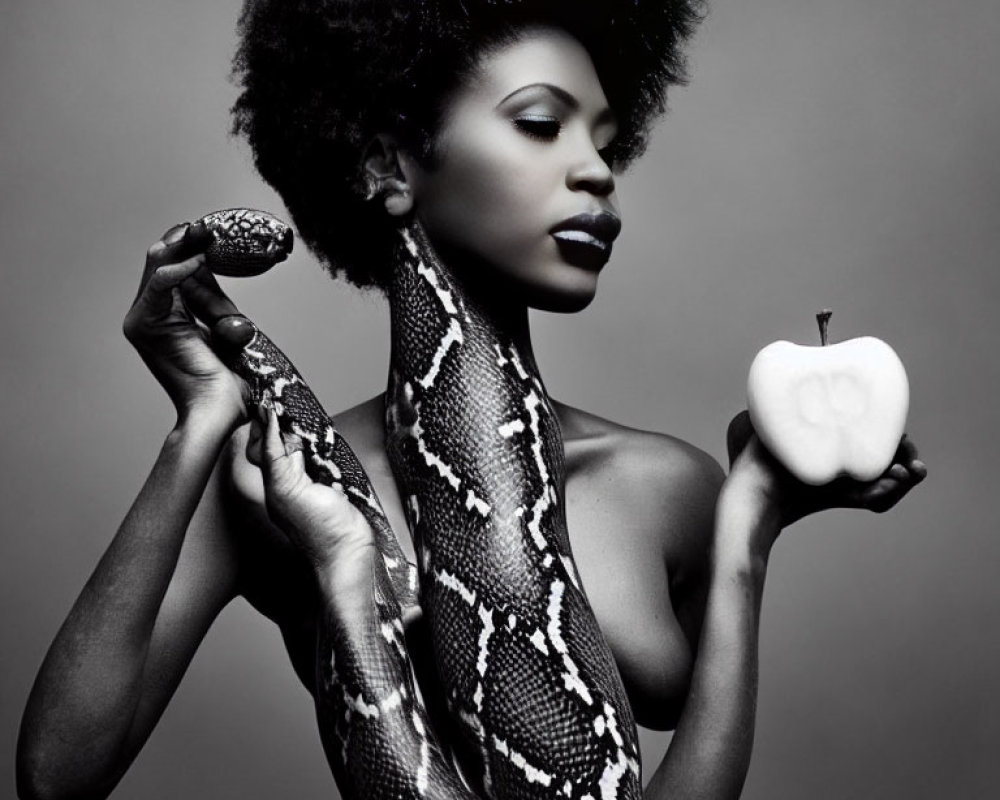 Monochrome portrait of woman with afro hairstyle holding snake and apple