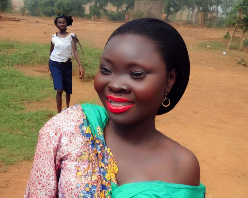 Smiling woman with red lipstick and hoop earrings, person walking on dirt road with trees and huts