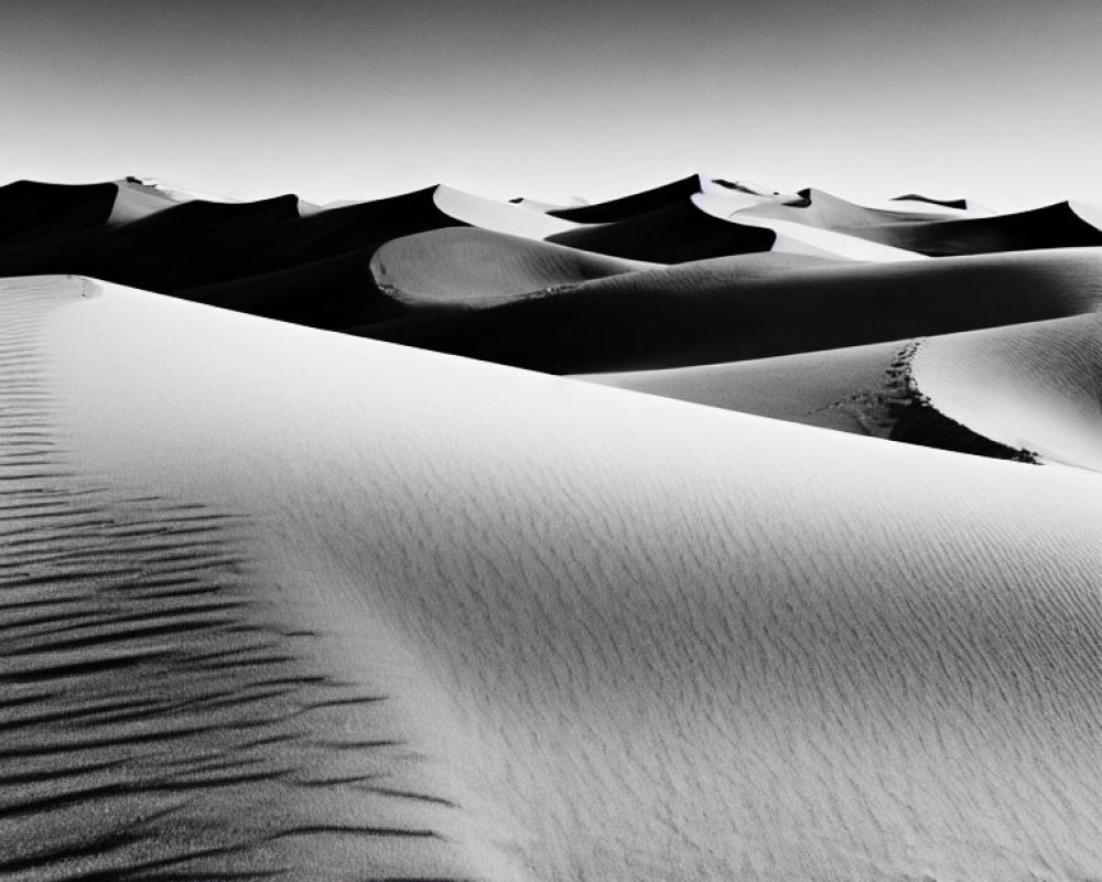 Monochrome photo of sand dunes under clear sky