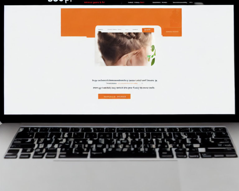 Laptop on Wooden Table Showing White and Orange Website Design with Woman Image and Text