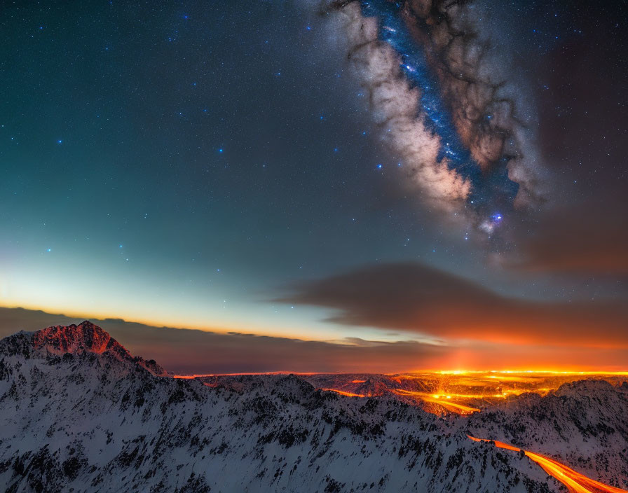 Snow-capped mountain range under starry sky with Milky Way and city lights glow