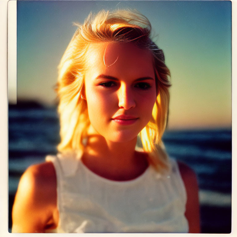 Blonde Woman in White Top at Sunset on Beach with Calm Expression