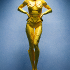 Golden humanoid statue on blue background with hands on hips