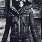 Skull mask and leather jacket person at metal door with gothic Halloween vibe