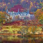 Autumn castle by lake with colorful foliage reflected in water