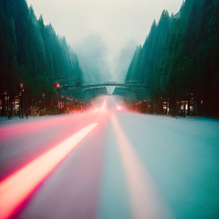 Twilight tree-lined street with car light streaks under arched bridge
