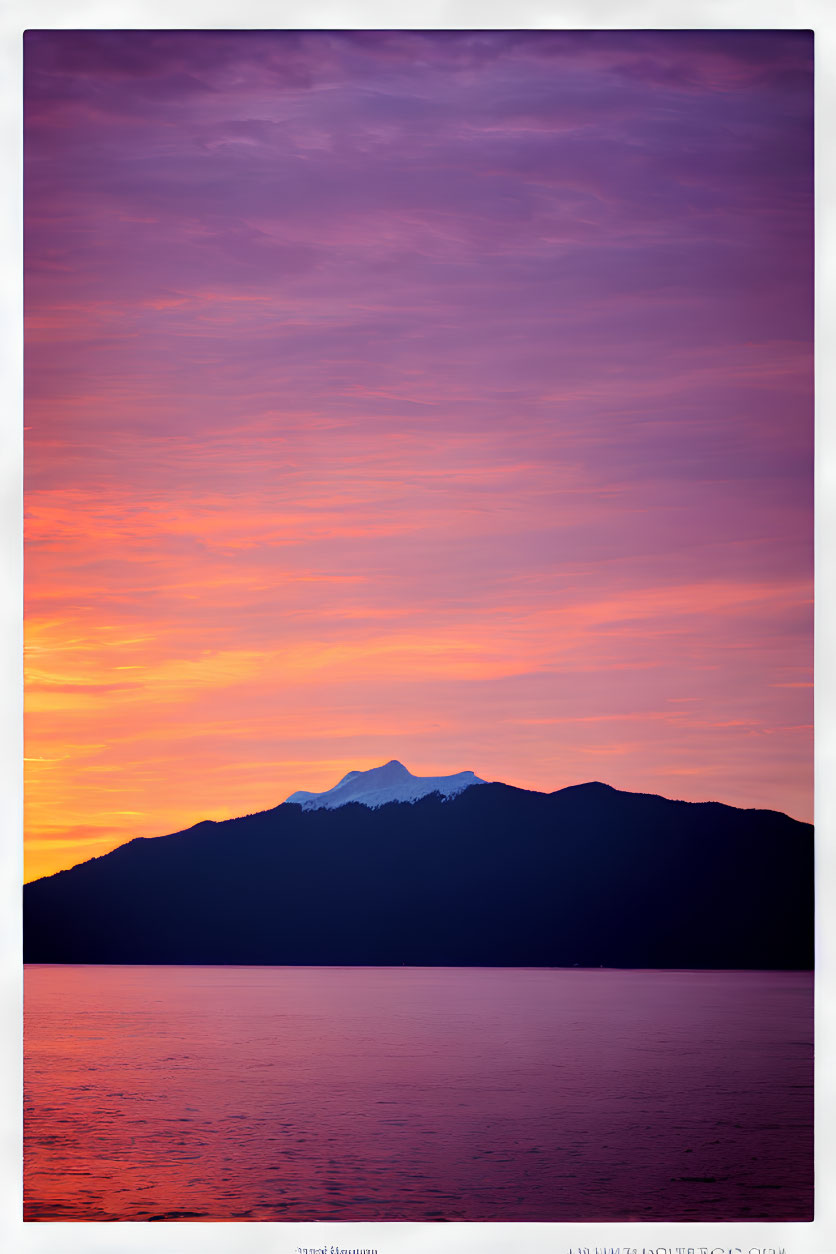 Colorful sunset over purple and orange mountains reflected in calm water