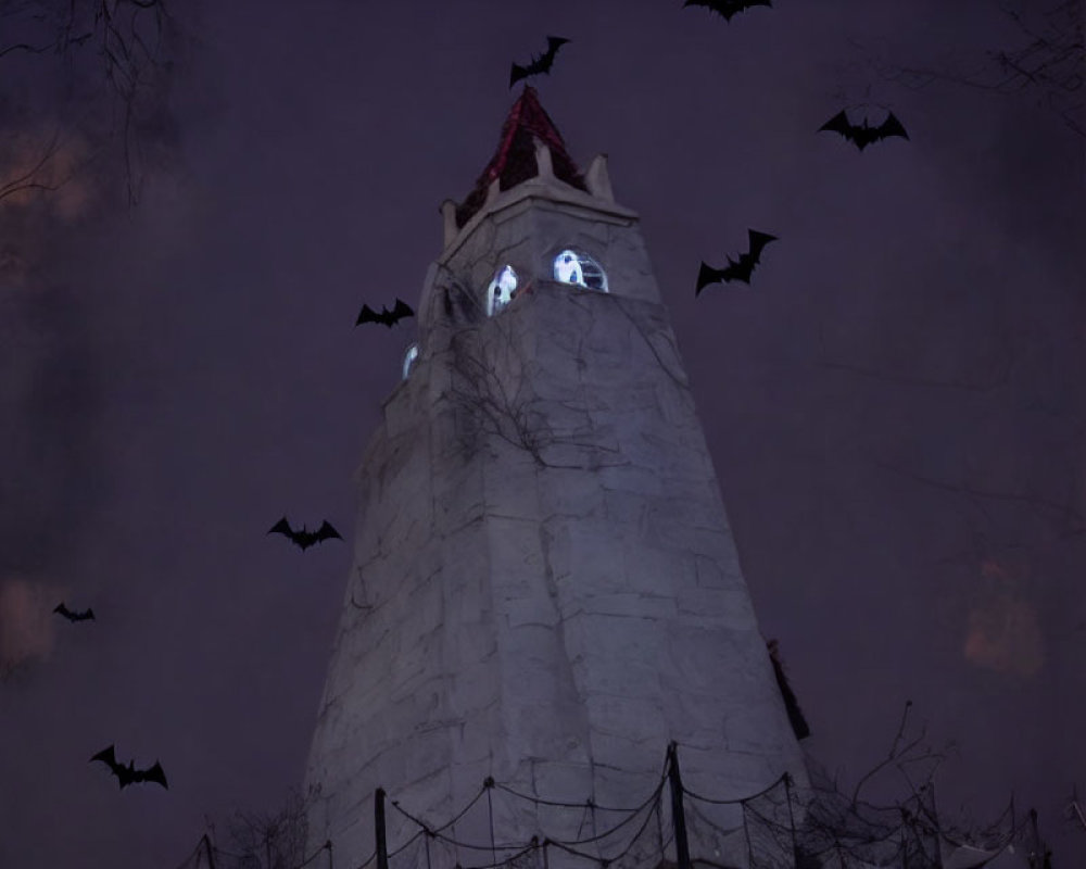 Gothic tower with glowing eyes windows and bats in dusky sky