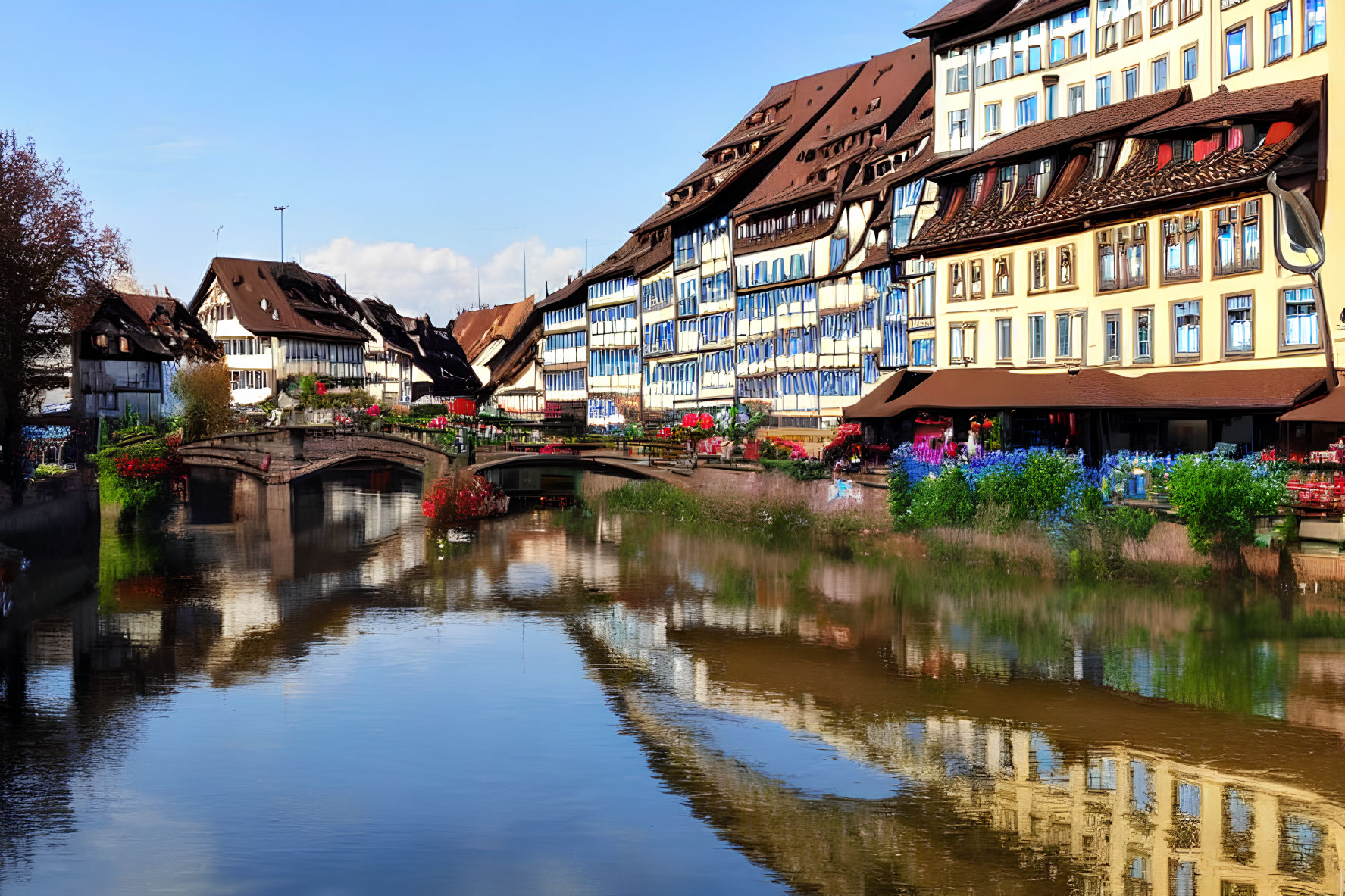 Tranquil river with timber-framed buildings and colorful flowers