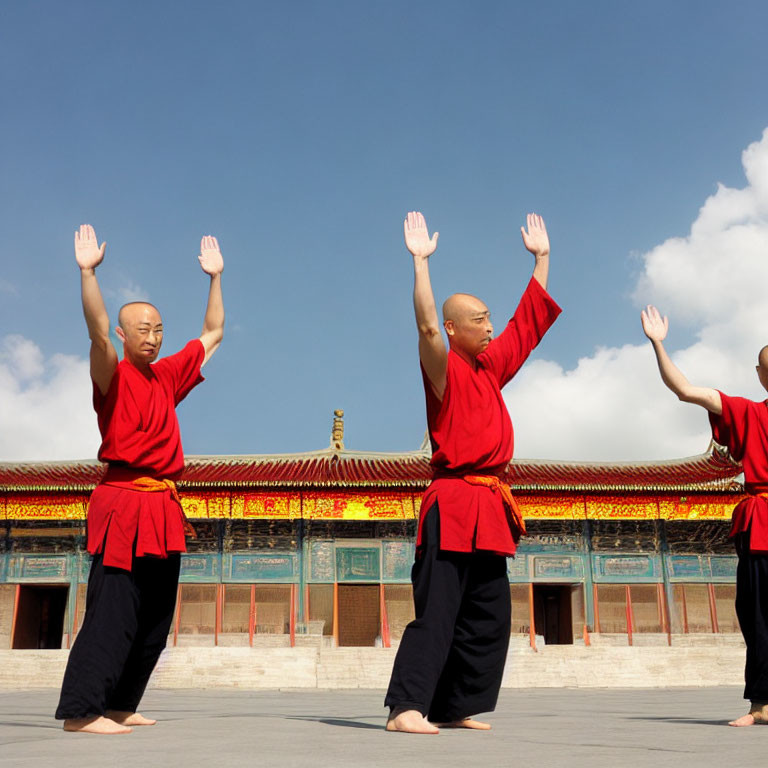 Three Individuals in Red Robes Performing Synchronized Martial Arts Routine
