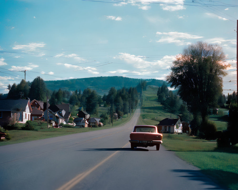Vintage Red Car Driving on Tranquil Rural Road at Dusk