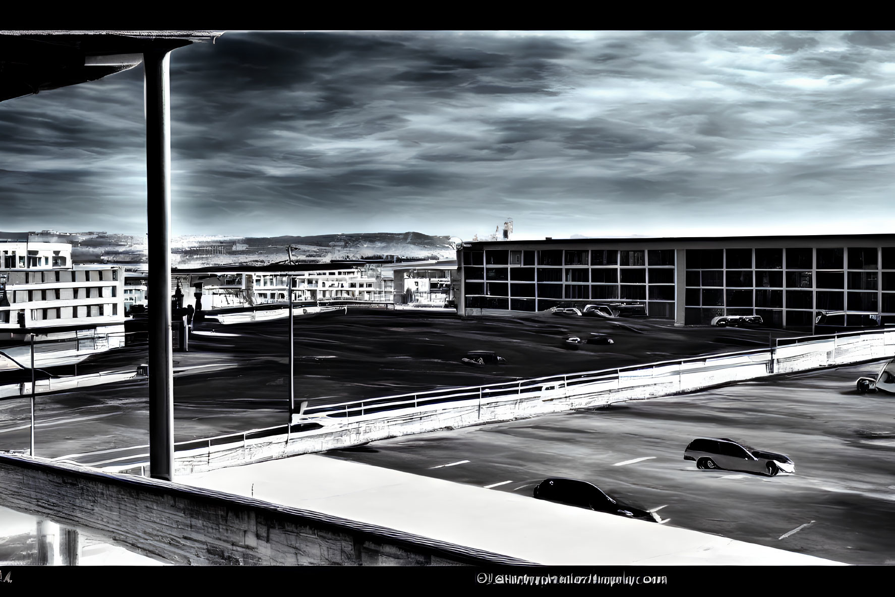 High-contrast parking lot scene with cars and buildings under dramatic sky