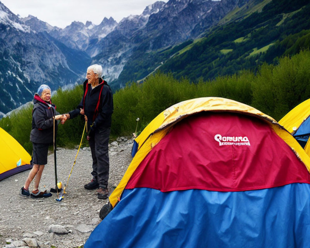 Elderly hikers with walking sticks in front of tents amidst green valleys and mountain peaks