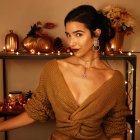 Stylish woman in V-neck sweater with sleek updo and silver jewelry under warm fairy lights