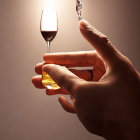 Hand holding wine glass with red wine pouring on warm-toned backdrop