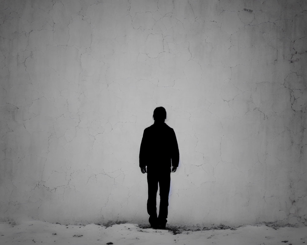 Silhouette of person against textured wall with bright light source casting shadow