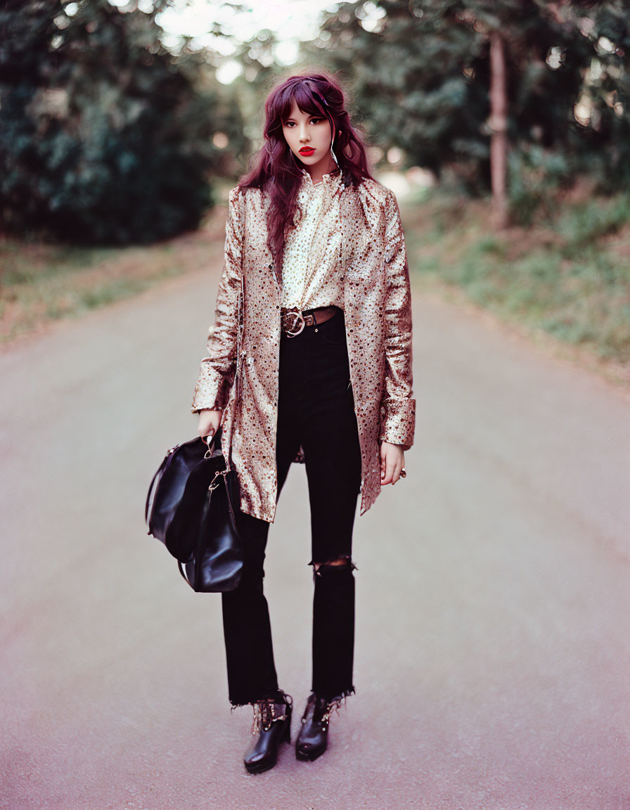Fashionable individual with fringe in gold blazer, white blouse, ripped jeans, and boots standing on
