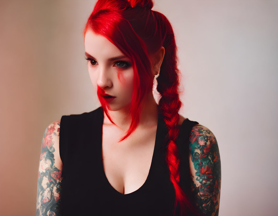 Serious woman with red hair and tattoos in black top and earring