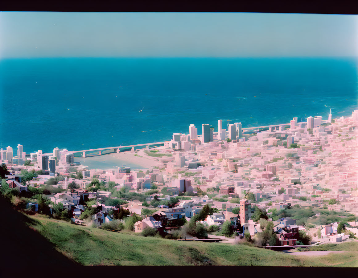 Urban coastal cityscape with skyscrapers, bridge, and sea view.