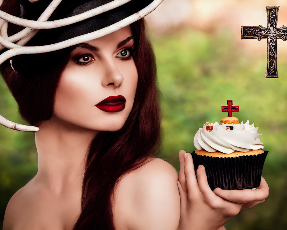 Dark-makeup woman holding cupcake with cross on hat, nature background