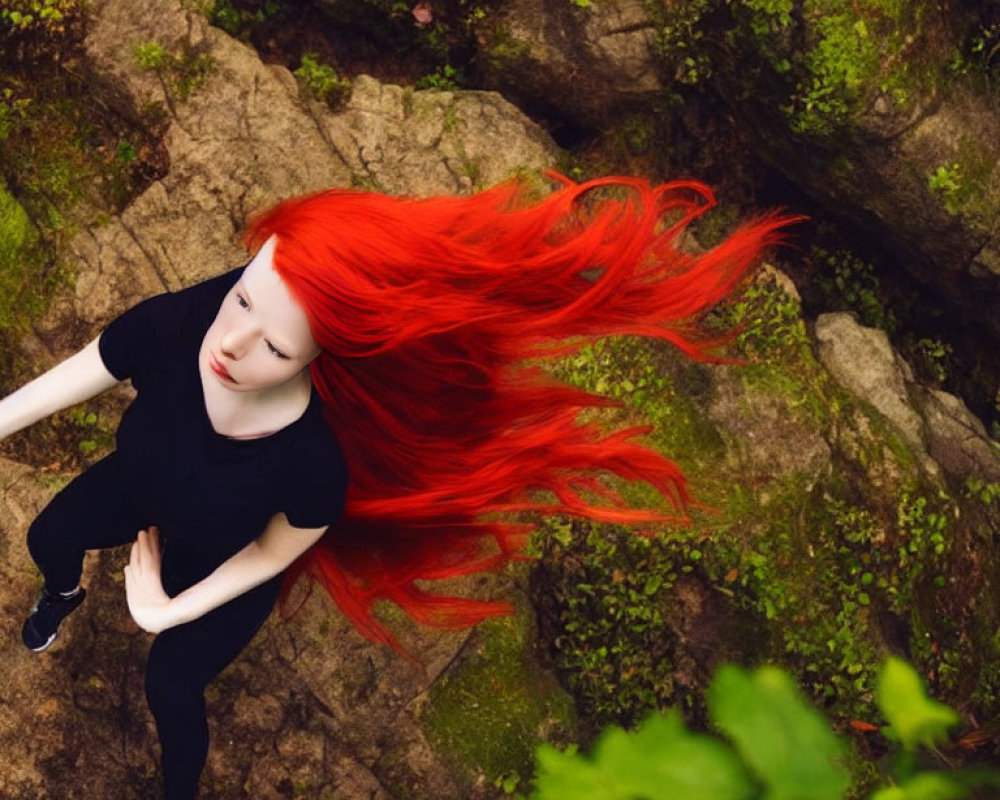Person with Bright Red Hair in Black Outfit on Rocky Forest Floor