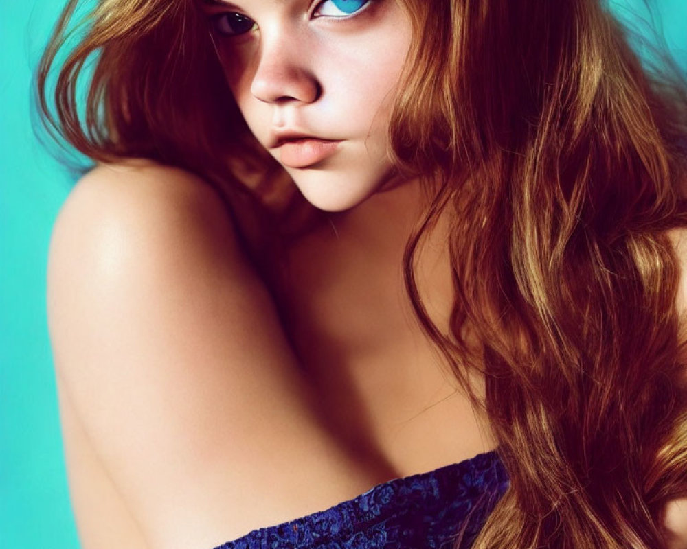 Young Person with Auburn Hair and Blue Eyes in Blue Off-Shoulder Garment on Teal Background