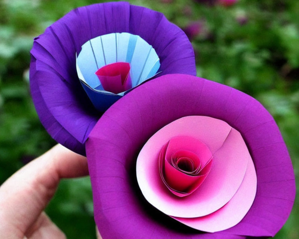 Handcrafted paper flowers: Purple and pink petals against green backdrop